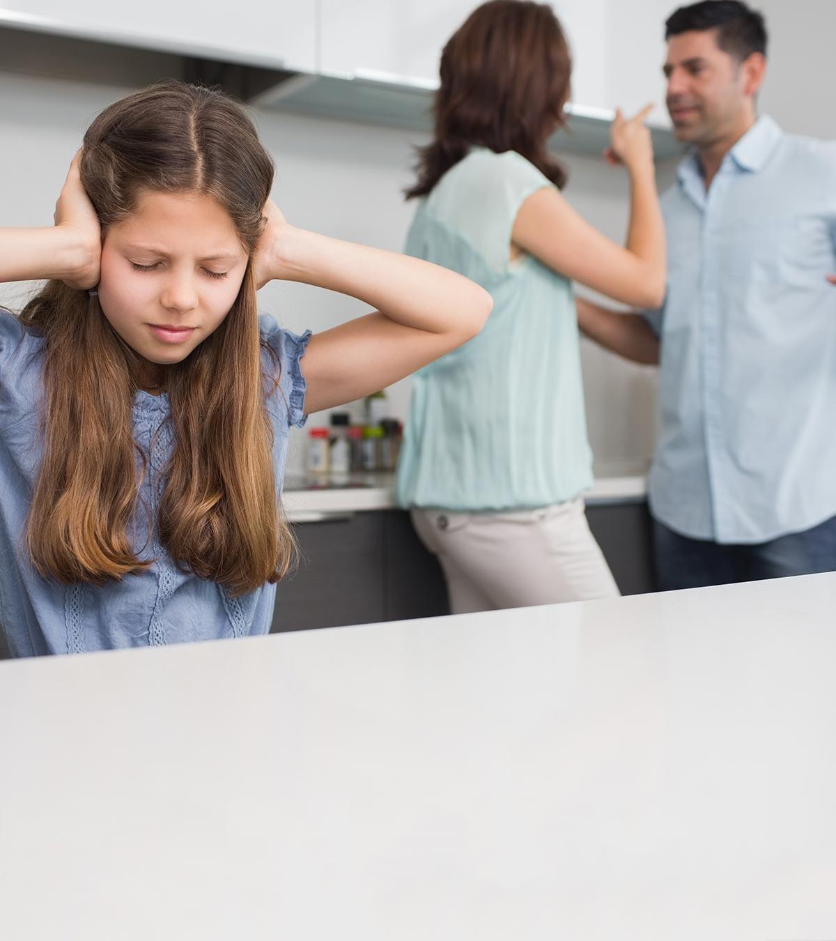 A small girl closes her ears with her hands while her parents are fighting