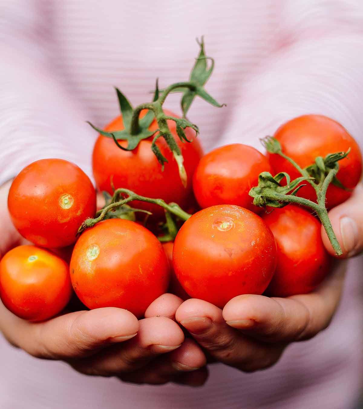 A lady holds lots of tomatoes