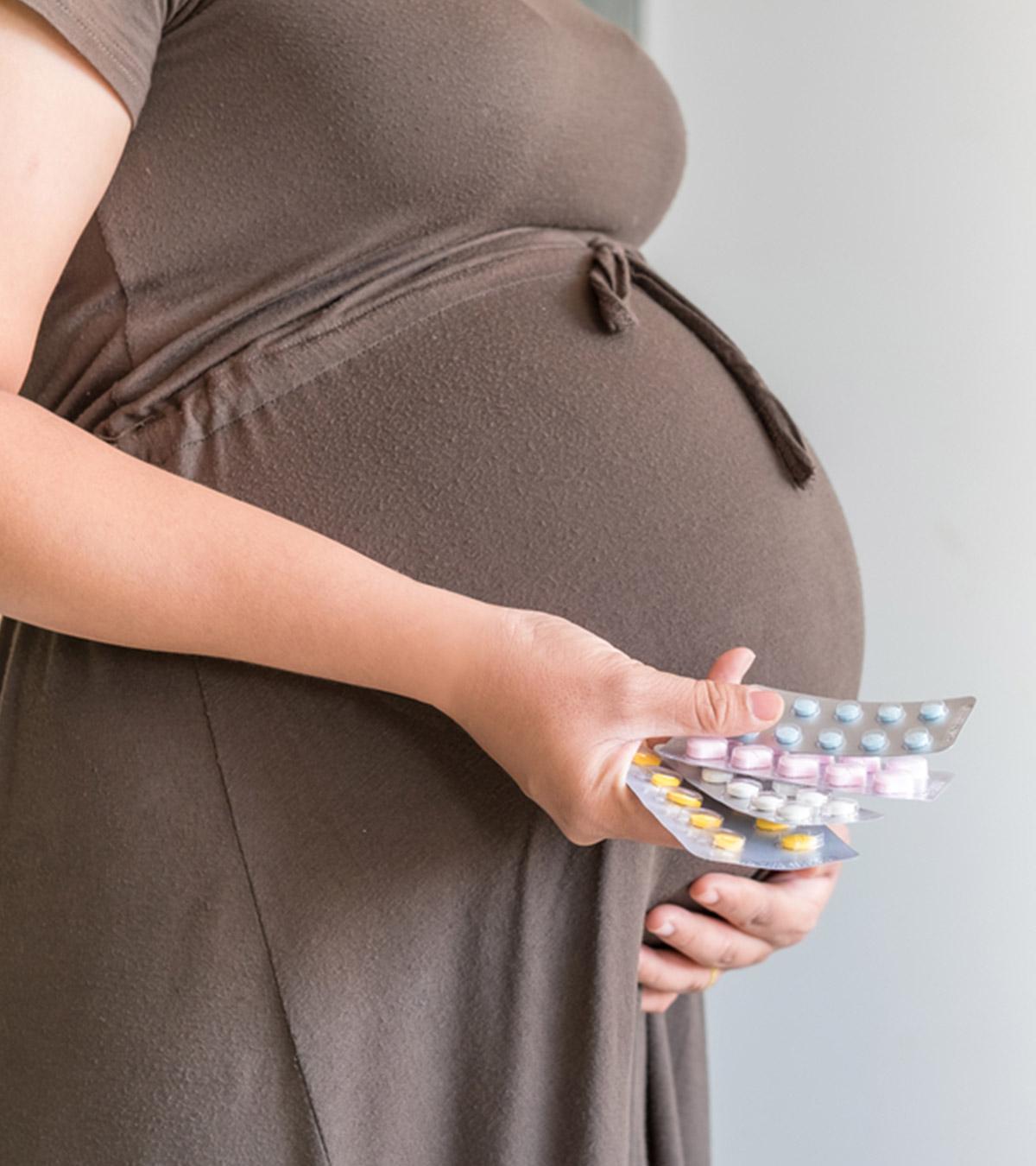 A pregnant lady holds lots of medicine strips
