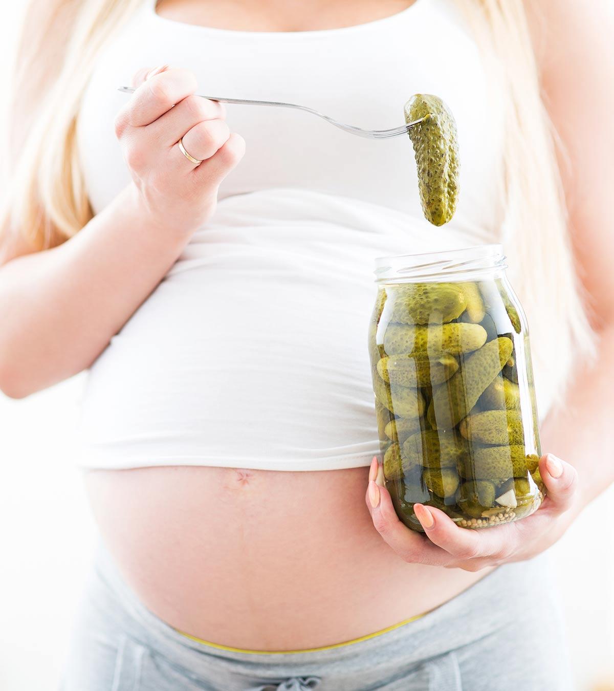 A pregnant woman holds a pickle jar