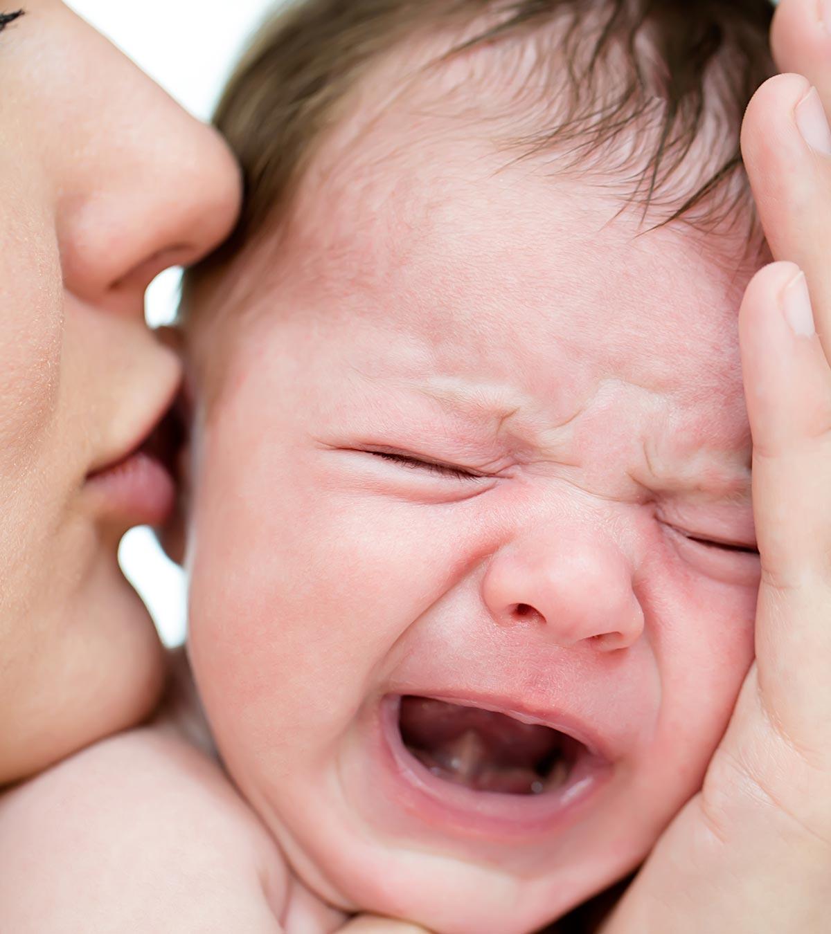 A mom kissing her baby while crying