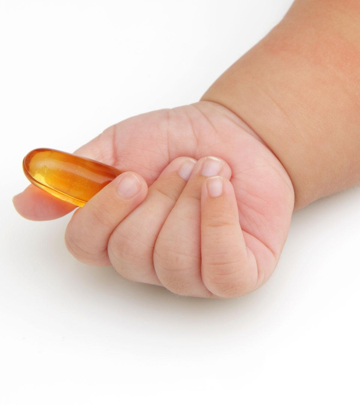 Baby holds a fish oil capsule