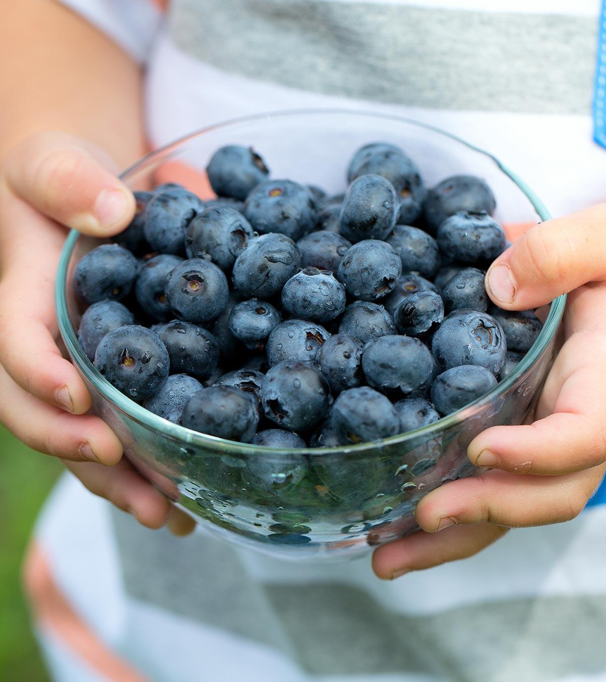 A kid holds lots of blueberries