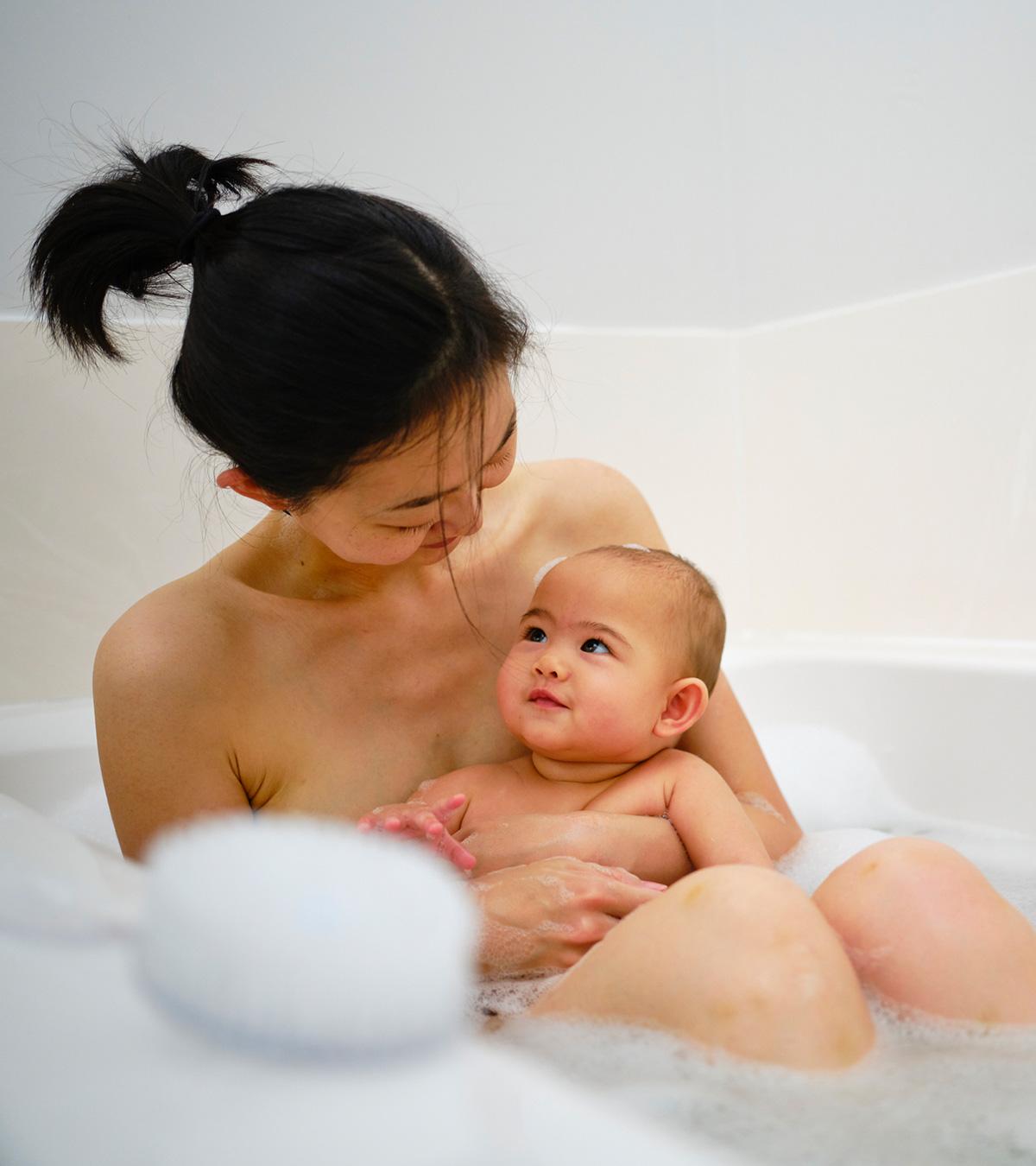 A mom and her baby both are taking a shower together
