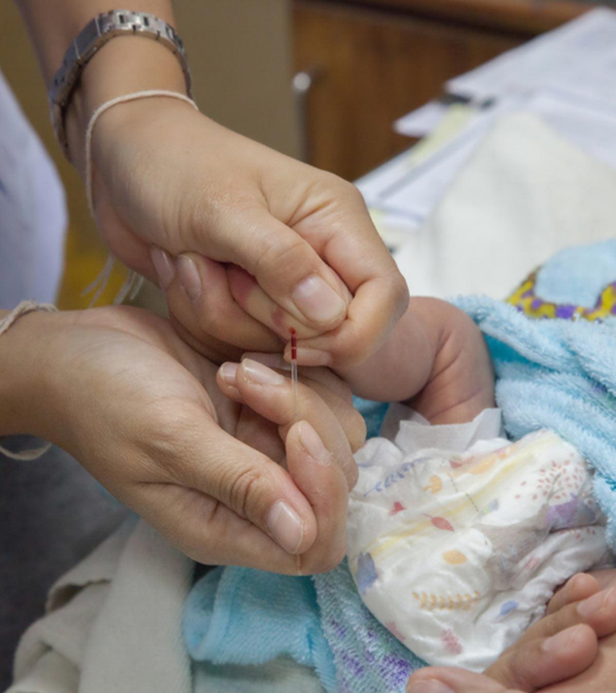 A doctor taking a blood sample from a newborn baby