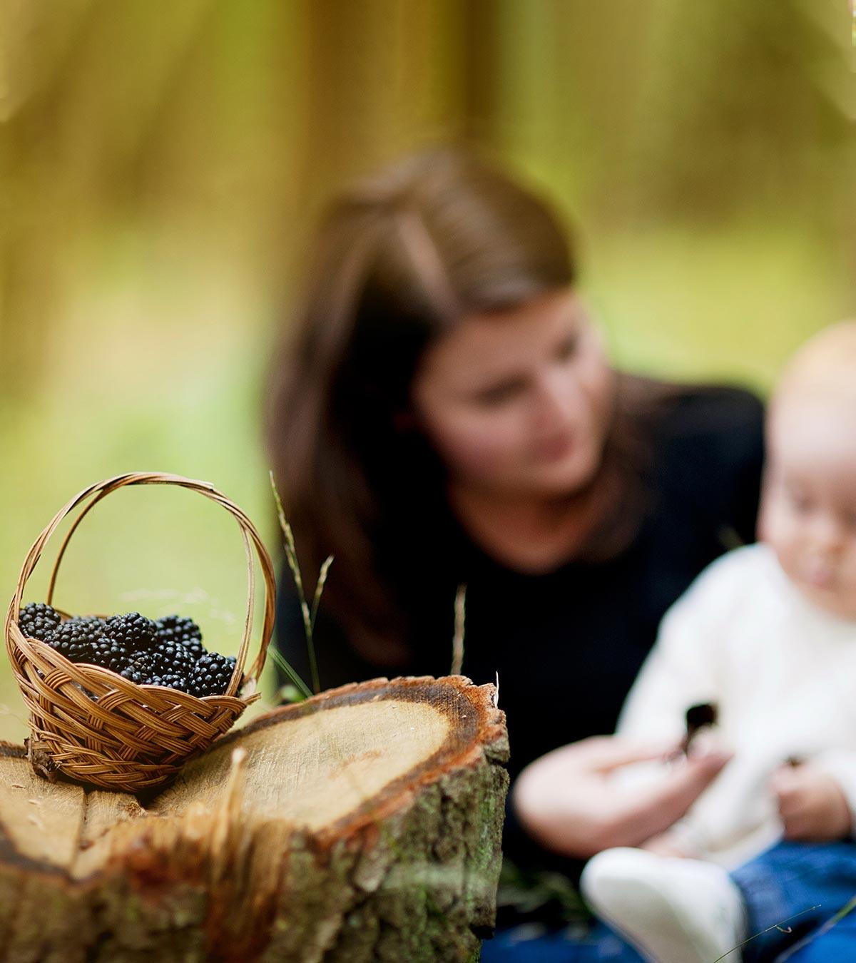 A mon gives blackberries to her baby