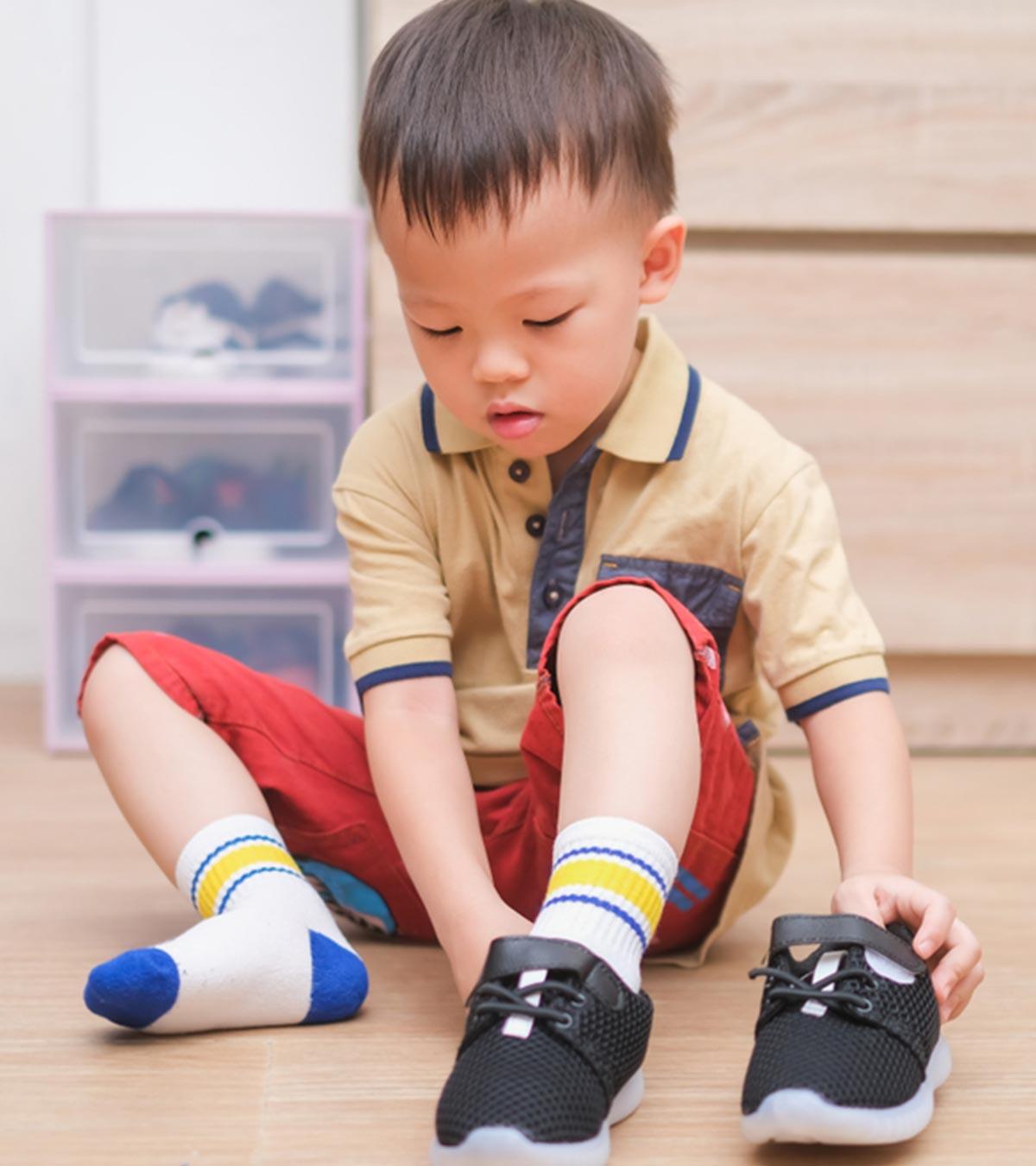 A kid wears shoes by himself