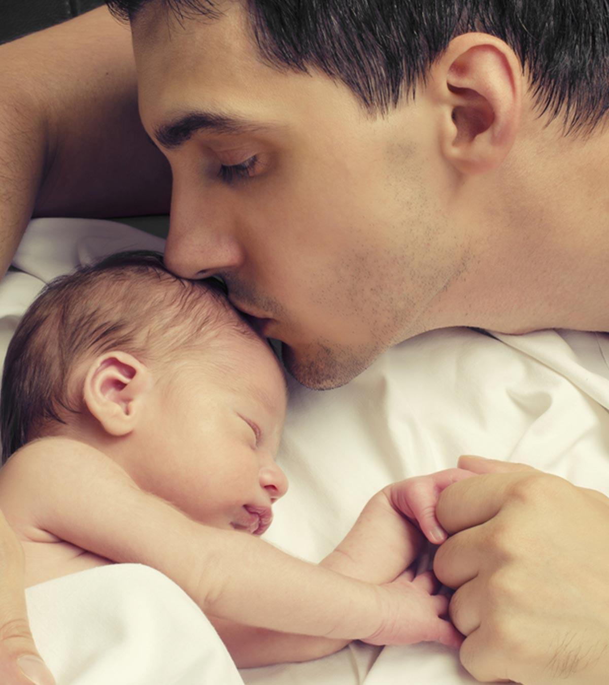 A dad kissing his newborn baby