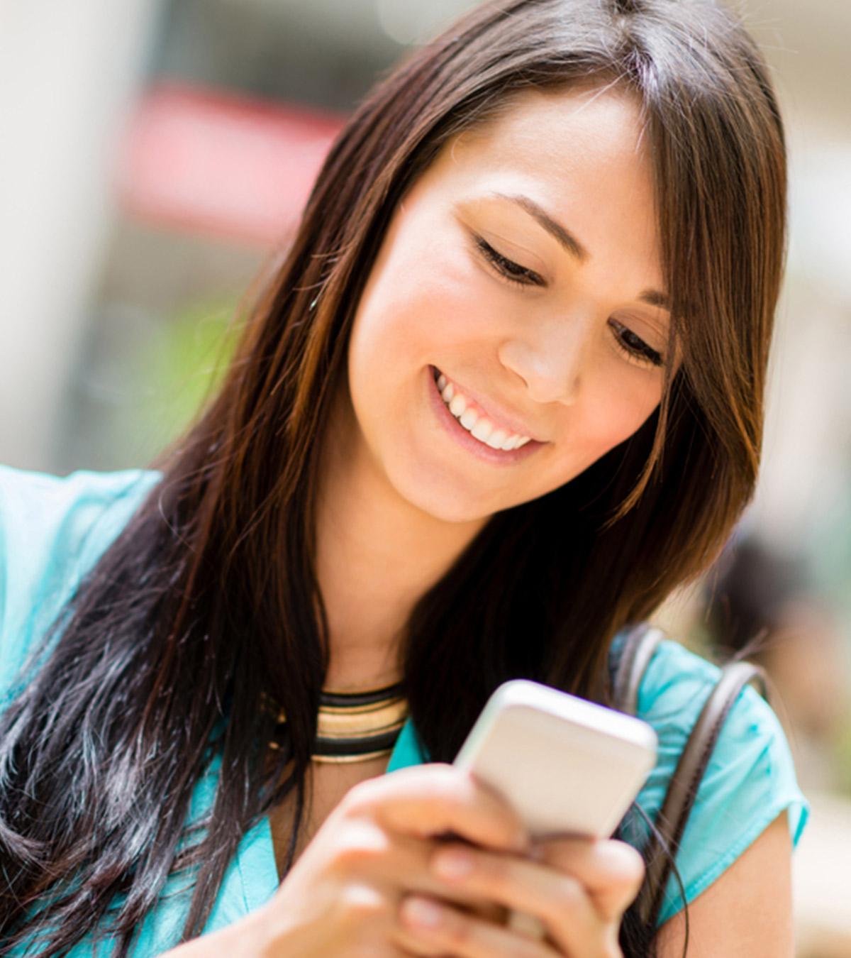 Woman smiling while reading a text message from a guy
