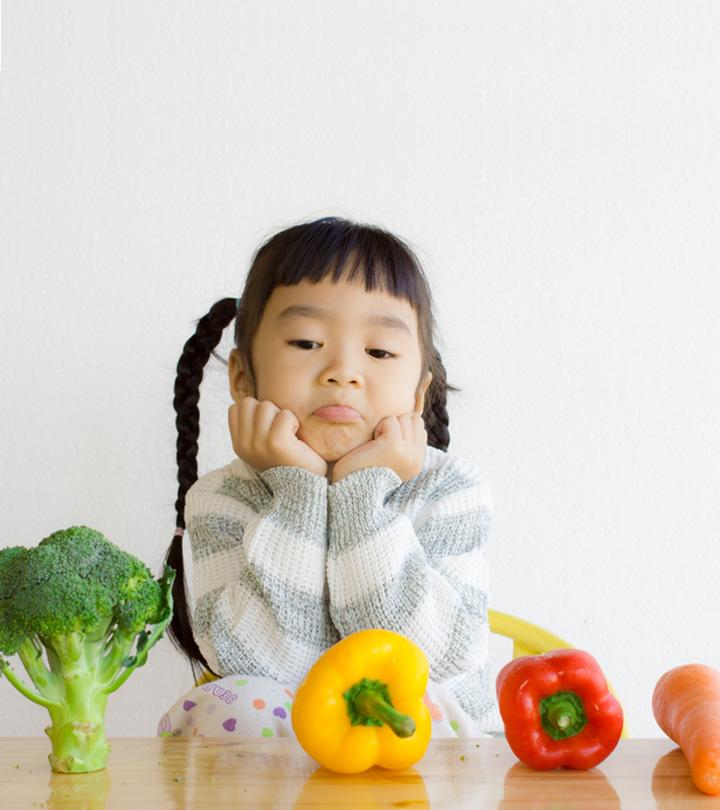A small kid with some broccoli and  bell peppers