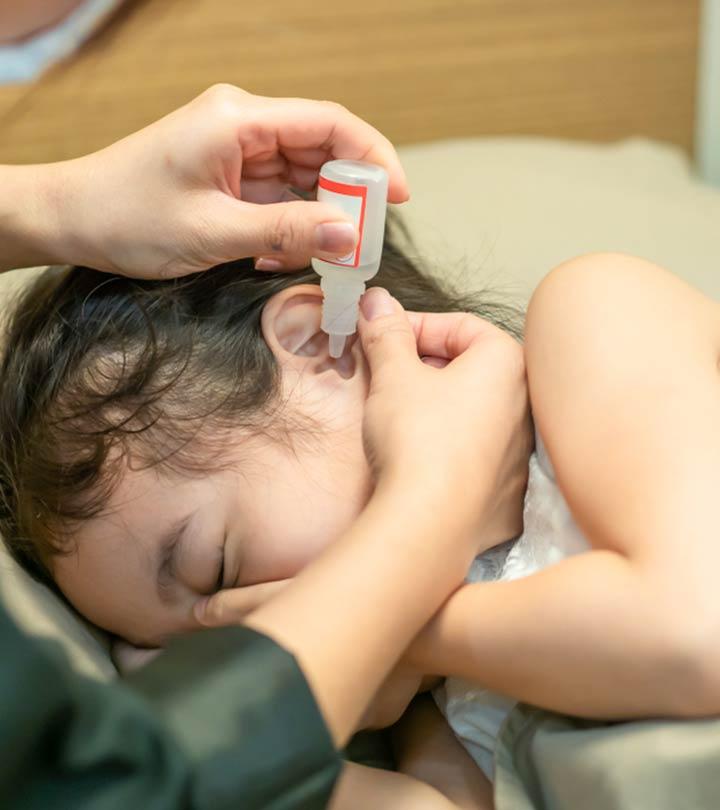 A mom putting eardrop on her baby